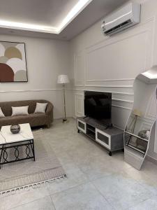 sala de estar con sofá y TV en وحدة سكنية مع كراج خاص للسيارة, en Bīshat Mushayţ