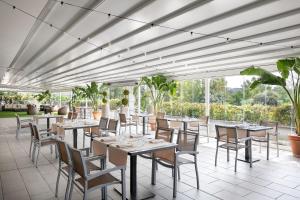 un restaurante con mesas, sillas y ventanas en Courtyard by Marriott Rome Central Park en Roma