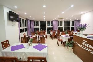 a restaurant with white tables and chairs and purple napkins at Lavender Nha Trang Hotel in Nha Trang +10 photos