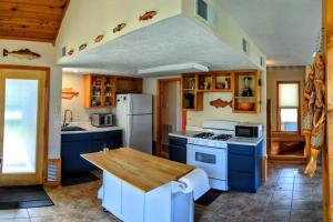 uma cozinha com armários azuis e um frigorífico branco em Fishing Cabin on White River w/ public boat ramp! em Norfork