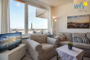 a living room with a couch and a tv and a window at Ferienhaus Seeblick - Wohnung 96 in Borkum