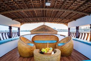 a boat with four chairs and a bowl of fruit at Why Not Houseboat in Alleppey