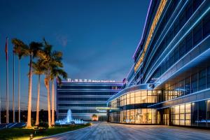 un grande edificio con palme di fronte di Mehood Elegant Hotel Guangzhou Baiyun Airport Huadu Cultural Tourism City a Huadong