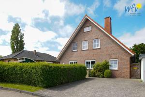 a large brick house with a driveway at Villa Robinson - Ferienwohnung Luv in Borkum
