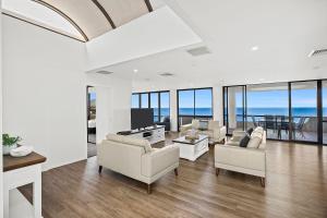 een woonkamer met witte meubels en uitzicht op de oceaan bij Pacific Towers Beach Resort in Coffs Harbour