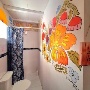uma casa de banho com uma flor pintada na parede em La Petite Maison em Assunção