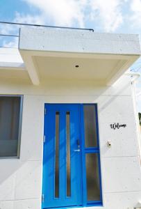 niebieskie drzwi na białym budynku w obiekcie 海之恋 w mieście Arazato