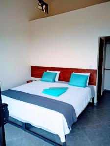 1 dormitorio con 1 cama grande con almohadas azules en VILLA SIMONE FRENCH ECOLODGE, en Tilarán