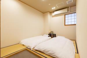 two white beds in a room with a window at Hostel OGK in Osaka