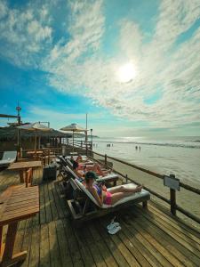 a group of people laying in lounge chairs on the beach at The Point Mancora - Beach Party Hostel in Máncora