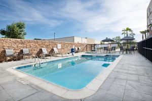 a pool with chairs and tables and a brick wall at Fairfield by Marriott Inn & Suites Chino in Chino