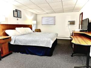 Budget Inn في Wellsville: غرفة نوم بسرير ومكتب وجهاز كمبيوتر