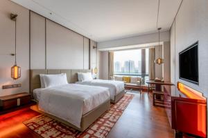 - une chambre avec un grand lit et une télévision dans l'établissement HUALUXE Beijing Xinan, à Pékin