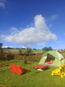 een groene tent en picknicktafels in een veld bij ZONA VERDE PRIVADA PARA ACAMPAR trae tu carpa o aquí te la alquilamos, in Suesca