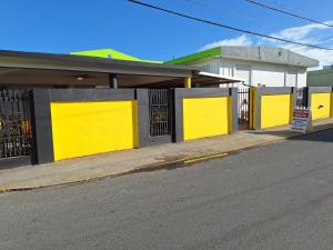 a building with yellow doors on the side of a street at Humacao guest house in Humacao