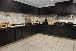 a kitchen with black cabinets and a white tile floor at Residence Inn by Marriott Fayetteville Cross Creek in Fayetteville