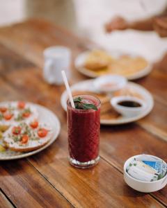 een drankje zittend op een houten tafel met borden eten bij Hotel Cielo y Selva in Punta Allen