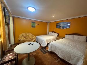 a room with two beds and a table and a chair at Hotel Elegant in Cajamarca