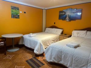 カハマルカにあるHotel Elegantのベッド2台とテーブルが備わるホテルルームです。