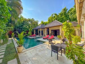 a house with a swimming pool with a table and chairs at Villa Bugis Abimanyu Seminyak in Seminyak
