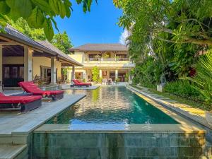 a house with a swimming pool in front of a house at Villa Bugis Abimanyu Seminyak in Seminyak