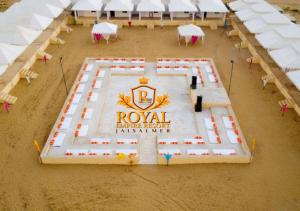 einen großen Pool mit Tischen und weißen Sonnenschirmen in der Unterkunft Royal Empire Resort Jaisalmer in Jaisalmer