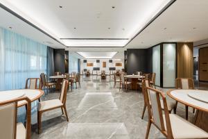 comedor con mesas y sillas en Mehood Elegant Hotel Guangzhou Baiyun Airport Huadu Cultural Tourism City, en Huadong