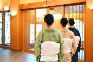 Trzy gejszy stojące w korytarzu patrzące w klatkę w obiekcie Seizan Yamato w mieście Ito