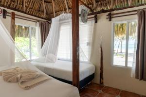 two beds in a room with two windows at Hotel Cielo y Selva in Punta Allen