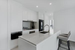 a white kitchen with a counter and a chair at Panoramic Lake View 2-Bed with Pool, Gym and BBQ in Belconnen