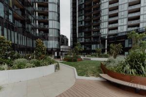 a park in the middle of two tall buildings at Panoramic Lake View 2-Bed with Pool, Gym and BBQ in Belconnen