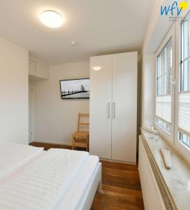 a white bedroom with a bed and a bathroom at Luv und Lee - Ferienwohnung Juister Stuv in Juist