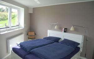 a bed with blue sheets in a bedroom with a window at Haus Kiek in't Watt Ferienwohnung Deichrausch in Juist