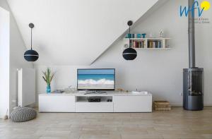 uma sala de estar branca com uma televisão numa parede branca em Haus Kiek in't Watt- Ferienwohnung Quartier 7 Ost em Juist