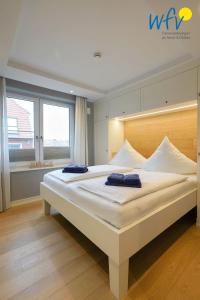 a bedroom with a large bed with two blue towels on it at Achterhus - Ferienwohnung Wattwurm in Juist