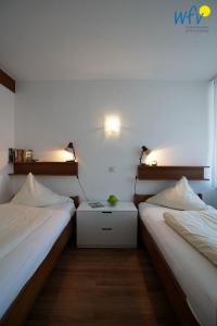 a room with two beds and a nightstand between them at Ferienhaus Seeblick - Wohnung 26 in Borkum
