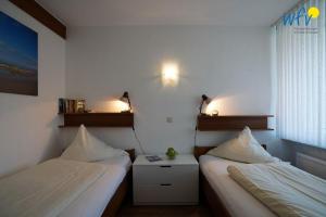 a room with two beds and a table and lights at Ferienhaus Seeblick - Wohnung 26 in Borkum