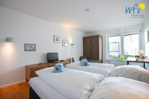 a room with three beds and a desk and a television at Appartement-Haus Regina Ferienwohnung Sonnendeck in Borkum