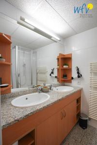 a bathroom with two sinks and a large mirror at Appartement-Haus Regina Ferienwohnung Sonnendeck in Borkum +23 photos