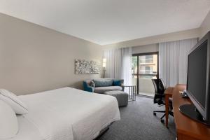 a hotel room with a bed and a tv at Courtyard Fort Myers Cape Coral in Fort Myers