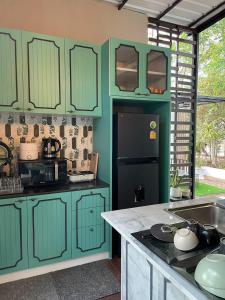 a kitchen with green cabinets and a black refrigerator at 356 Hostel in Thung Song