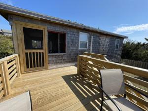 a wooden deck with two chairs and a house at SUNFISH COVE cottage in Avon