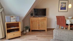 a living room with a television on a wooden cabinet at Landhaus-am-Golfplatz-9 in Sankt Peter-Ording