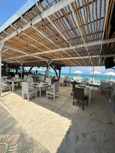 a patio with tables and chairs on the beach at Nusa Indah Bungalow in Nusa Lembongan