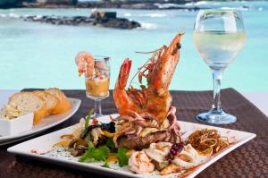 een bord met garnalen en een glas wijn bij Hotel Solymar in Puerto Ayora