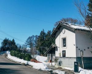 een klein wit gebouw met een klok erop bij サウナ付き一棟貸し別荘 "大岡辻-tsuji-oooka-" l "大岡温"泉入り放題 