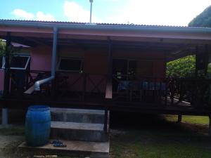 ein Haus mit einer Veranda und einem blauen Fass in der Unterkunft Sunset beach maupiti in Te-Fare-Arii