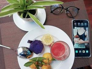 uma mesa com dois pratos de comida e um telemóvel em Hoi An Pho Library Hotel em Hoi An