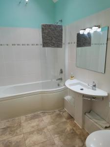 a bathroom with a tub and a sink and a mirror at The Brownlow Stables in Leighton Buzzard