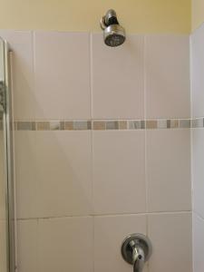 una ducha con una pared de azulejos blancos y una luz en The Brownlow Stables, en Leighton Buzzard